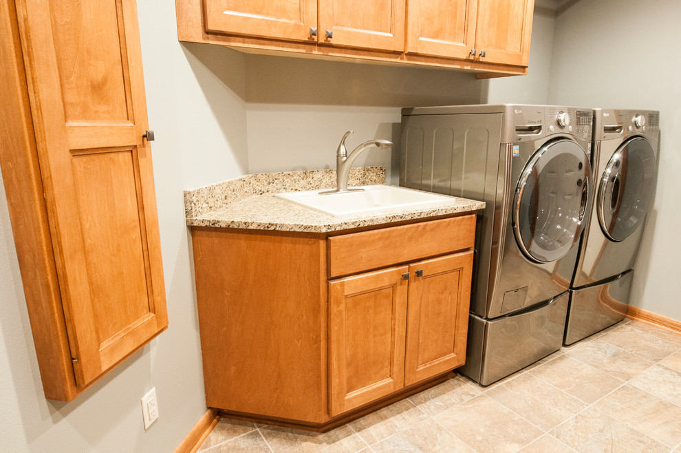 Medium sized traditional single-wall separated utility room in Milwaukee with a built-in sink, grey walls, a side by side washer and dryer, laminate countertops, ceramic flooring, recessed-panel cabinets and medium wood cabinets.