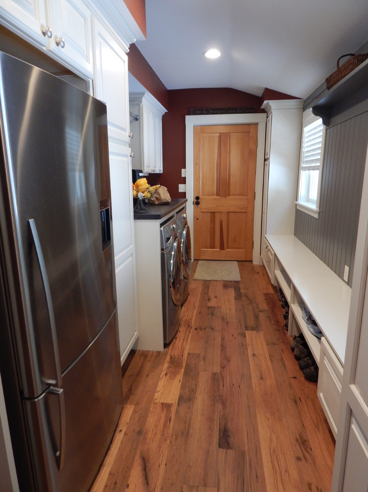 Inspiration for a timeless galley medium tone wood floor utility room remodel in Boston with a single-bowl sink, raised-panel cabinets, white cabinets, laminate countertops, red walls and a side-by-side washer/dryer