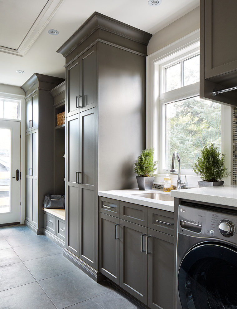 Example of a large transitional single-wall porcelain tile utility room design in Toronto with an undermount sink, shaker cabinets, gray cabinets, quartz countertops, gray walls, a side-by-side washer/dryer and white countertops