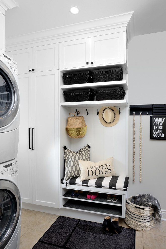Diseño de lavadero multiusos clásico renovado de tamaño medio con armarios estilo shaker, puertas de armario blancas, paredes grises, suelo de baldosas de cerámica, lavadora y secadora apiladas y suelo beige