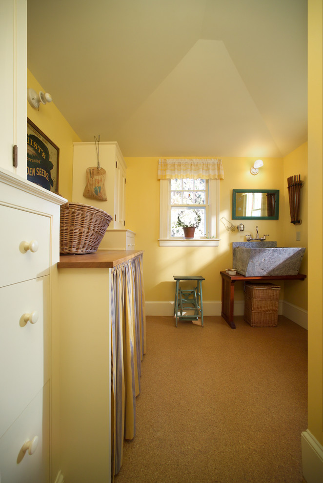 Large country single-wall separated utility room in Portland Maine with an utility sink, open cabinets, dark wood cabinets, wood worktops, yellow walls, laminate floors, a side by side washer and dryer, beige floors and brown worktops.