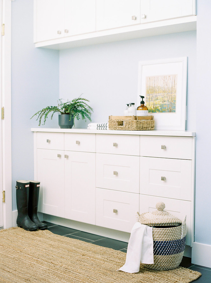Cette photo montre une buanderie parallèle chic multi-usage et de taille moyenne avec un placard à porte shaker, des portes de placard blanches, un plan de travail en quartz, un mur bleu, un sol en carrelage de porcelaine et un sol gris.