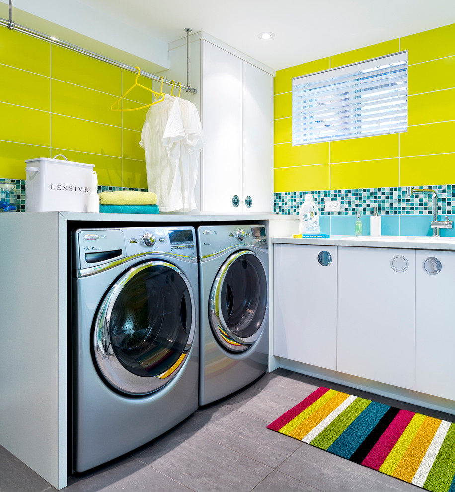 Idéer för att renovera en funkis tvättstuga enbart för tvätt, med släta luckor, vita skåp, gula väggar, en tvättmaskin och torktumlare bredvid varandra och grått golv