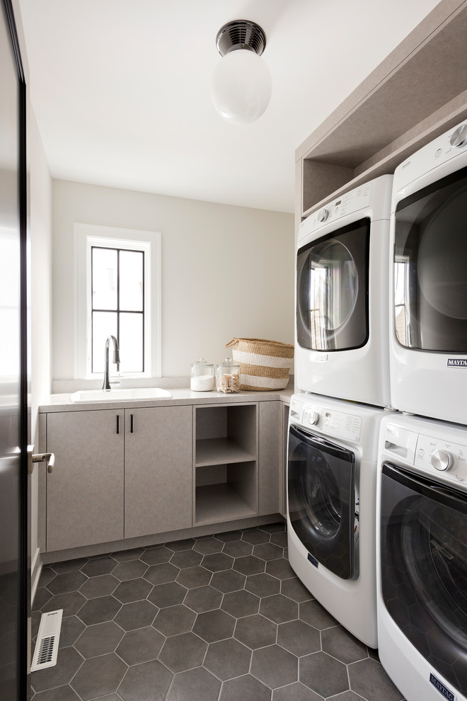 Imagen de cuarto de lavado campestre con fregadero encastrado, armarios con paneles lisos, puertas de armario grises, suelo gris, encimeras grises y paredes blancas
