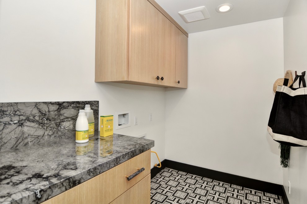 Photo of a medium sized classic single-wall separated utility room in Orange County with flat-panel cabinets, light wood cabinets, marble worktops, white walls, porcelain flooring, a side by side washer and dryer, black floors and grey worktops.