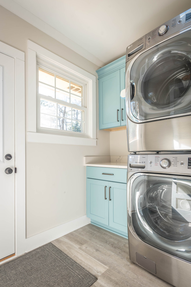Esempio di una piccola lavanderia moderna con ante con riquadro incassato, ante blu, paraspruzzi beige, pareti beige, parquet chiaro, lavatrice e asciugatrice a colonna, pavimento beige e top bianco