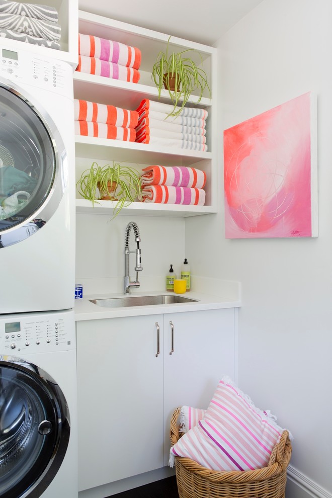 Exempel på en mellanstor modern u-formad tvättstuga enbart för tvätt, med släta luckor, vita skåp, vita väggar, en tvättpelare, en undermonterad diskho, mörkt trägolv och brunt golv
