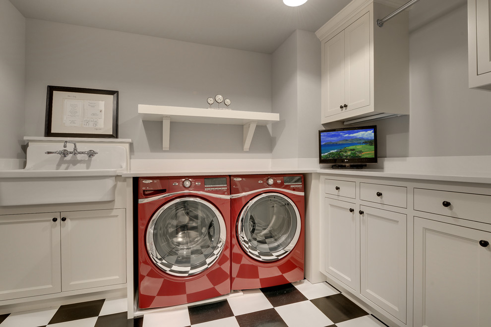 Immagine di una lavanderia tradizionale con lavello stile country, pareti grigie, ante bianche e pavimento multicolore