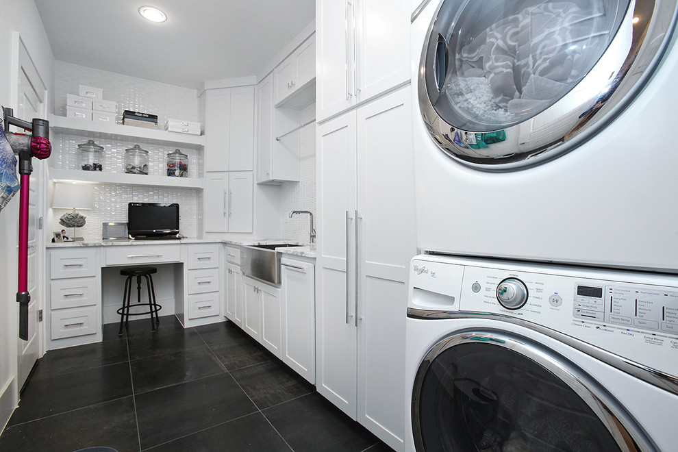 Inredning av en modern stor l-formad tvättstuga enbart för tvätt, med en rustik diskho, skåp i shakerstil, grå skåp, marmorbänkskiva, vita väggar, klinkergolv i porslin, en tvättpelare och grått golv