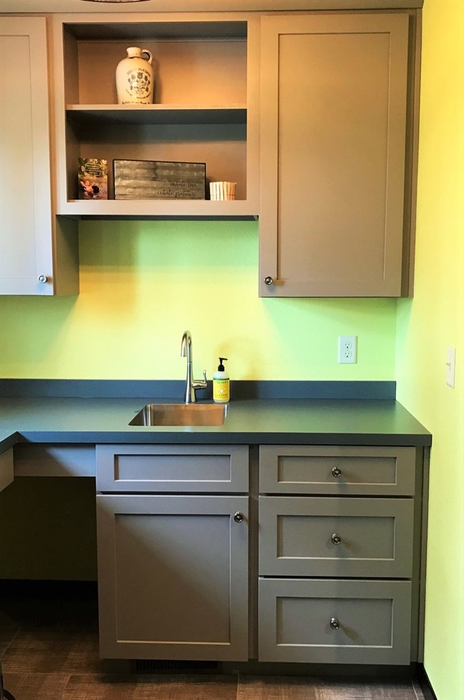 Photo of a medium sized traditional separated utility room in Other with a submerged sink, shaker cabinets, grey cabinets, laminate countertops, yellow walls, vinyl flooring and a stacked washer and dryer.