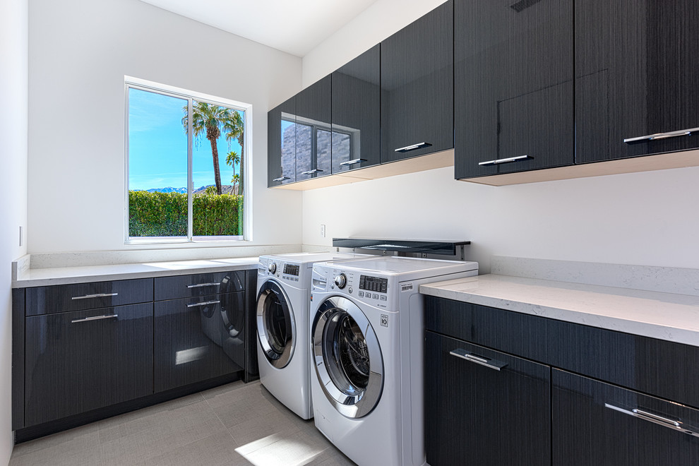 Modelo de cuarto de lavado en L vintage de tamaño medio con armarios con paneles lisos, puertas de armario grises, paredes blancas y lavadora y secadora juntas
