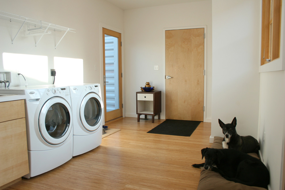 Idee per una lavanderia multiuso di medie dimensioni con lavello sottopiano, ante lisce, ante in legno chiaro, pareti beige, pavimento in bambù e lavatrice e asciugatrice affiancate