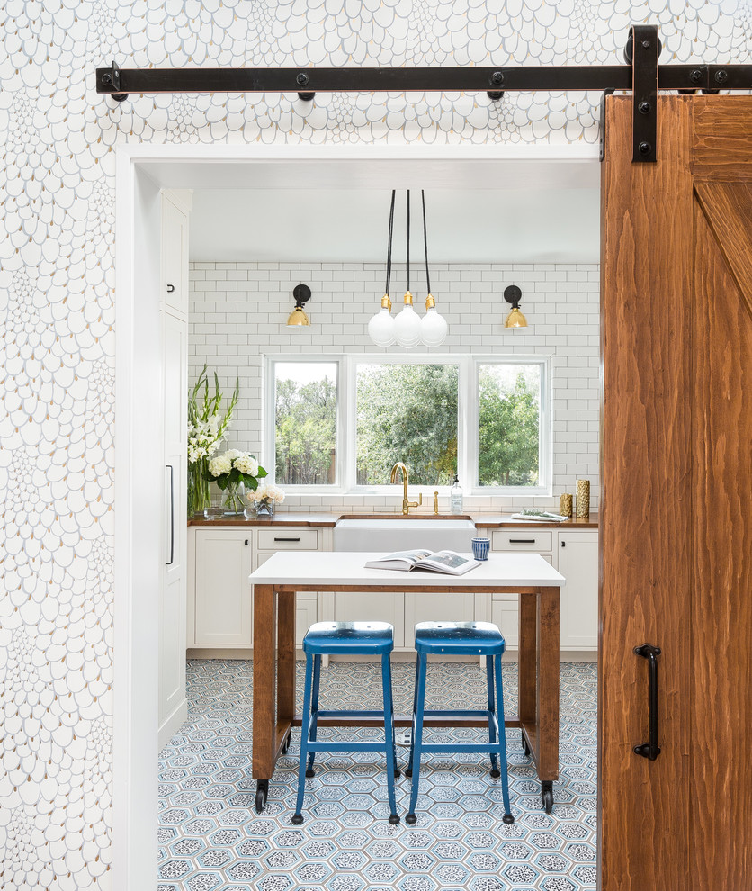 Inspiration for a modern terra-cotta tile and blue floor laundry room remodel in Albuquerque with a farmhouse sink, white cabinets, wood countertops, white walls, a concealed washer/dryer, white countertops and shaker cabinets