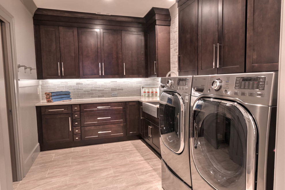 Photo of a medium sized traditional l-shaped separated utility room in Atlanta with a belfast sink, shaker cabinets, dark wood cabinets, engineered stone countertops, grey walls, porcelain flooring, a side by side washer and dryer, beige floors and white worktops.