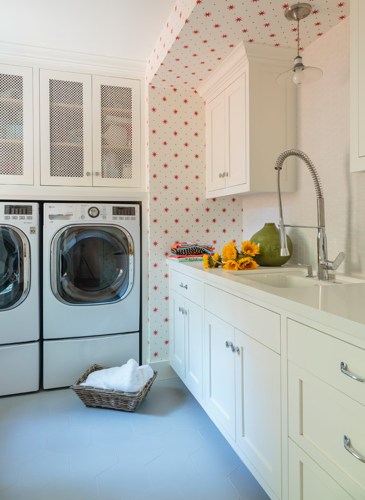 Lantlig inredning av en mellanstor u-formad tvättstuga enbart för tvätt, med en undermonterad diskho, skåp i shakerstil, vita skåp, röda väggar, klinkergolv i porslin och en tvättmaskin och torktumlare bredvid varandra
