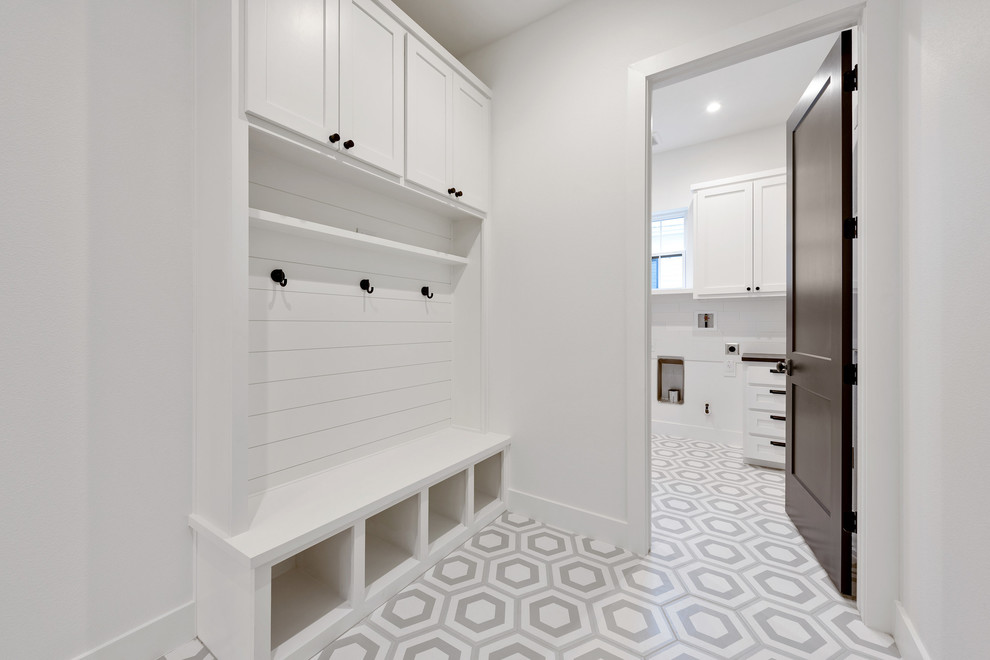 Inspiration for a mid-sized farmhouse porcelain tile and gray floor utility room remodel in Austin with an undermount sink, shaker cabinets, white cabinets, quartz countertops, white walls, a side-by-side washer/dryer and black countertops