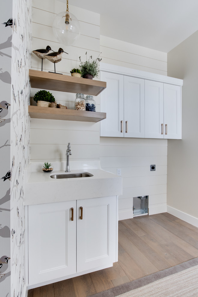 Farmhouse single-wall light wood floor utility room photo in Salt Lake City with an undermount sink, a side-by-side washer/dryer, shaker cabinets, white cabinets, quartzite countertops, multicolored walls and white countertops