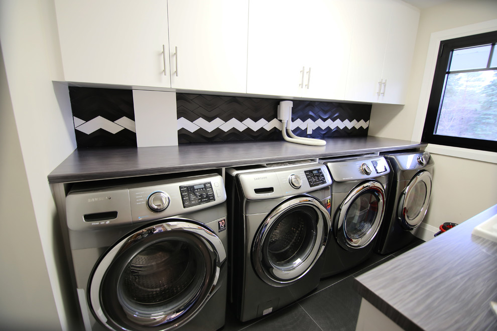 Zweizeilige, Mittelgroße Klassische Waschküche mit Einbauwaschbecken, flächenbündigen Schrankfronten, weißen Schränken, Arbeitsplatte aus Holz, beiger Wandfarbe, Waschmaschine und Trockner nebeneinander und grauer Arbeitsplatte in Toronto