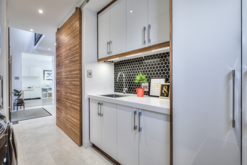 Photo of a small modern galley utility room in Toronto with a submerged sink, flat-panel cabinets, medium wood cabinets, engineered stone countertops, white walls, porcelain flooring, a stacked washer and dryer, grey floors and white worktops.