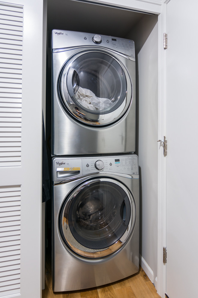 Foto di una piccola lavanderia multiuso moderna con ante lisce, ante grigie, pareti grigie, parquet chiaro e lavatrice e asciugatrice a colonna