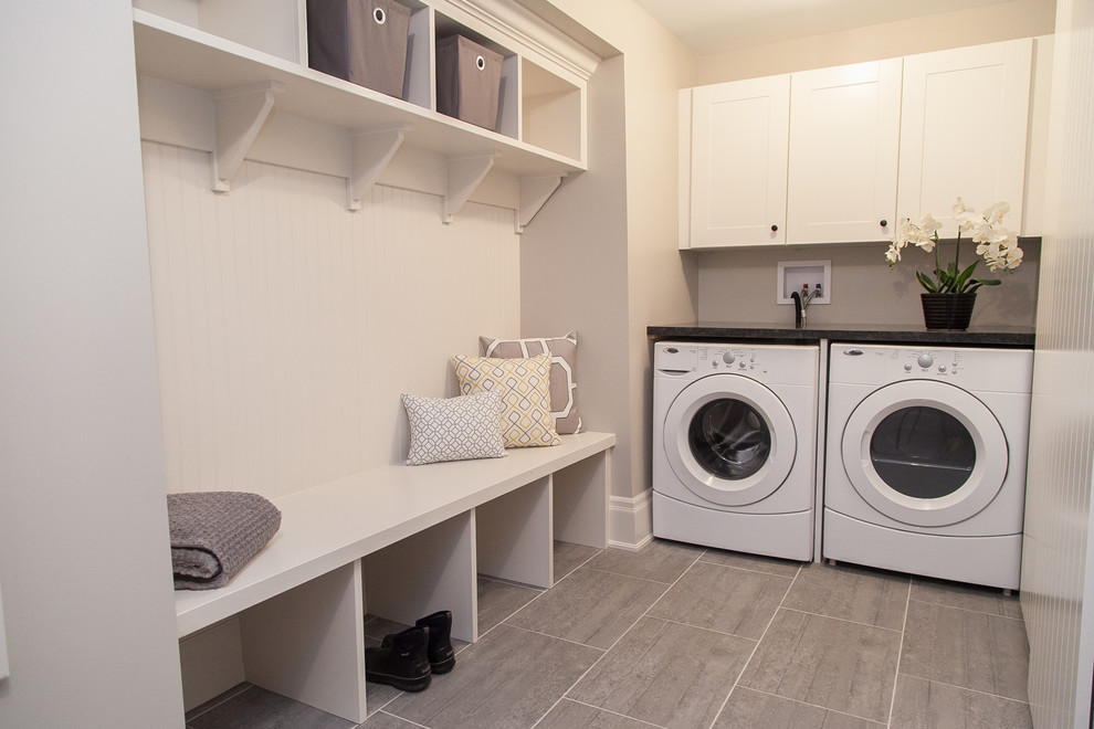Foto di una grande lavanderia multiuso minimalista con ante in stile shaker, ante bianche, top in granito, pareti grigie, pavimento con piastrelle in ceramica e lavatrice e asciugatrice affiancate