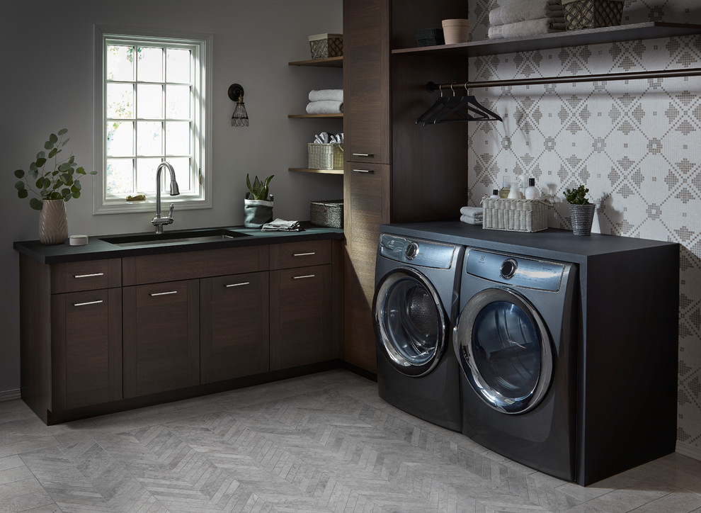 Ispirazione per una lavanderia multiuso minimalista di medie dimensioni con lavello sottopiano, ante lisce, ante in legno bruno, pareti bianche, lavatrice e asciugatrice affiancate e pavimento grigio