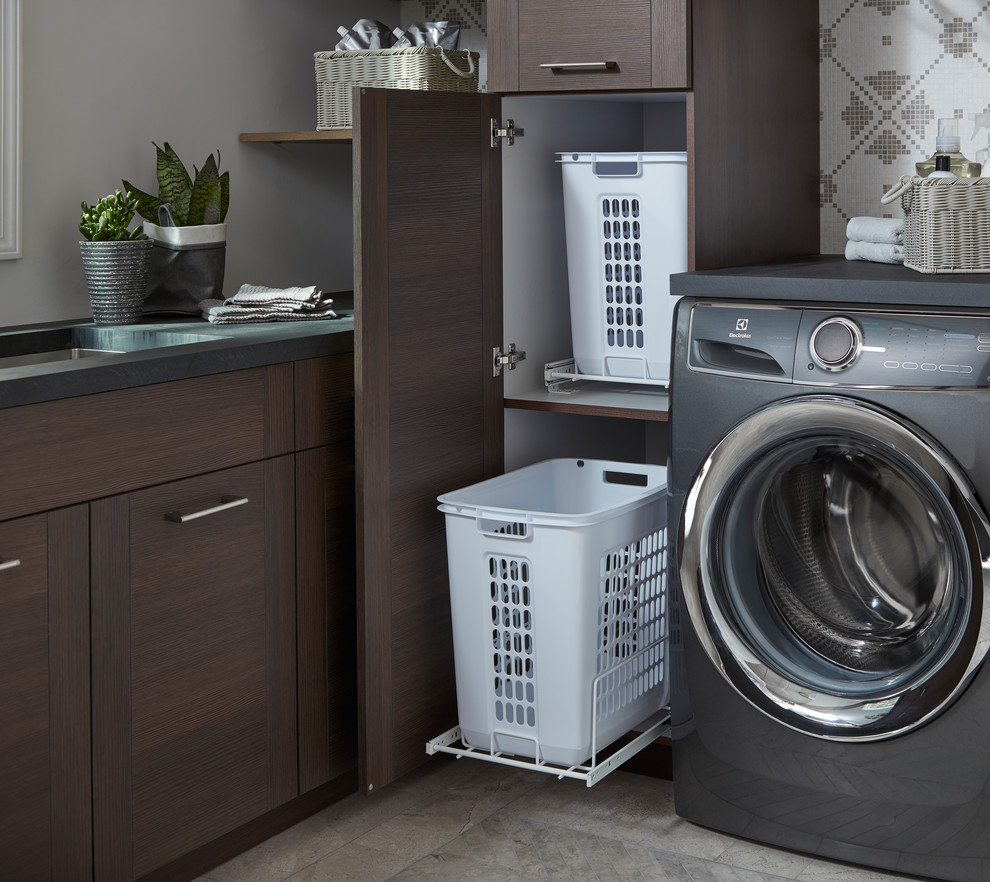 Idee per una lavanderia multiuso minimalista di medie dimensioni con lavello sottopiano, ante lisce, ante in legno bruno, lavatrice e asciugatrice affiancate, pavimento grigio e pareti grigie