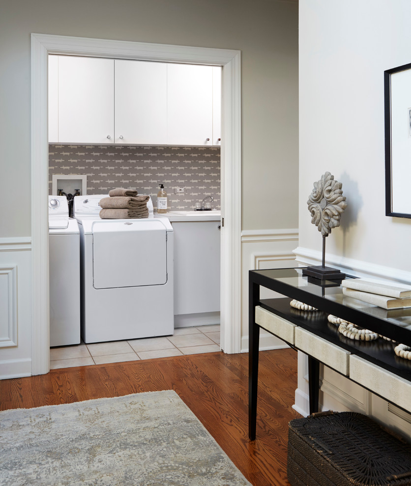 Esempio di una sala lavanderia classica di medie dimensioni con ante lisce, ante bianche, pareti beige, parquet scuro, lavatrice e asciugatrice affiancate e pavimento marrone