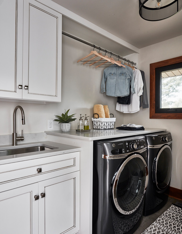 This is an example of a medium sized rustic single-wall utility room in Other with a submerged sink, recessed-panel cabinets, white cabinets, engineered stone countertops, white walls, porcelain flooring, a side by side washer and dryer, grey floors and white worktops.