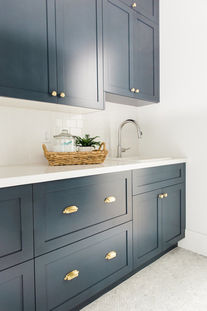 Exempel på en klassisk tvättstuga, med en nedsänkt diskho, blå skåp, vita väggar och skåp i shakerstil