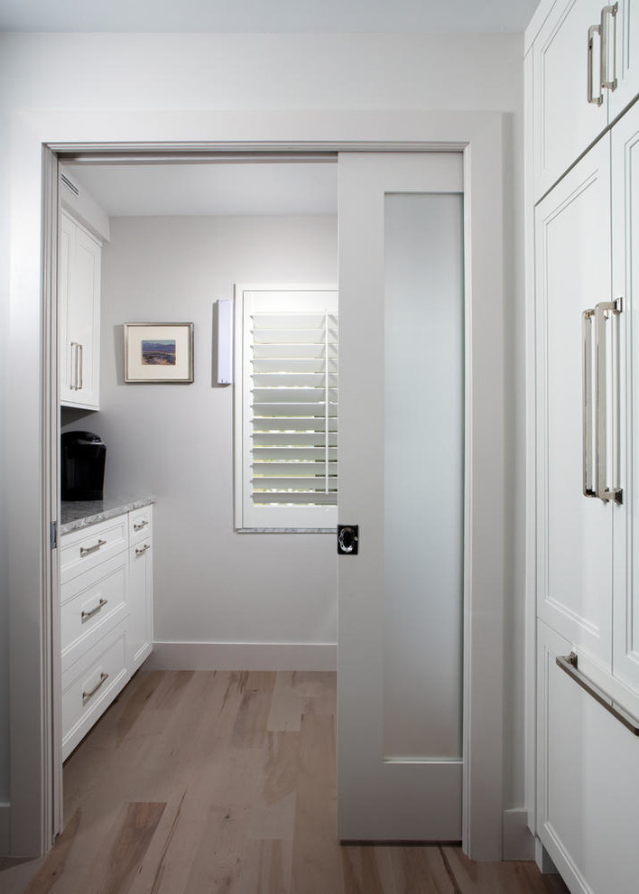 Idéer för en stor modern parallell tvättstuga enbart för tvätt, med luckor med infälld panel, vita skåp, bänkskiva i kvarts, vita väggar, mellanmörkt trägolv och en tvättpelare