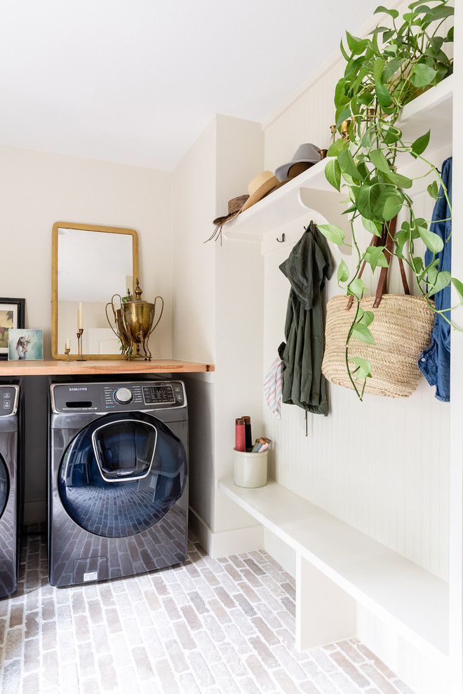 Foto di una lavanderia multiuso chic di medie dimensioni con lavatoio, ante bianche, top in legno, pareti bianche, pavimento in mattoni, lavatrice e asciugatrice affiancate e top marrone