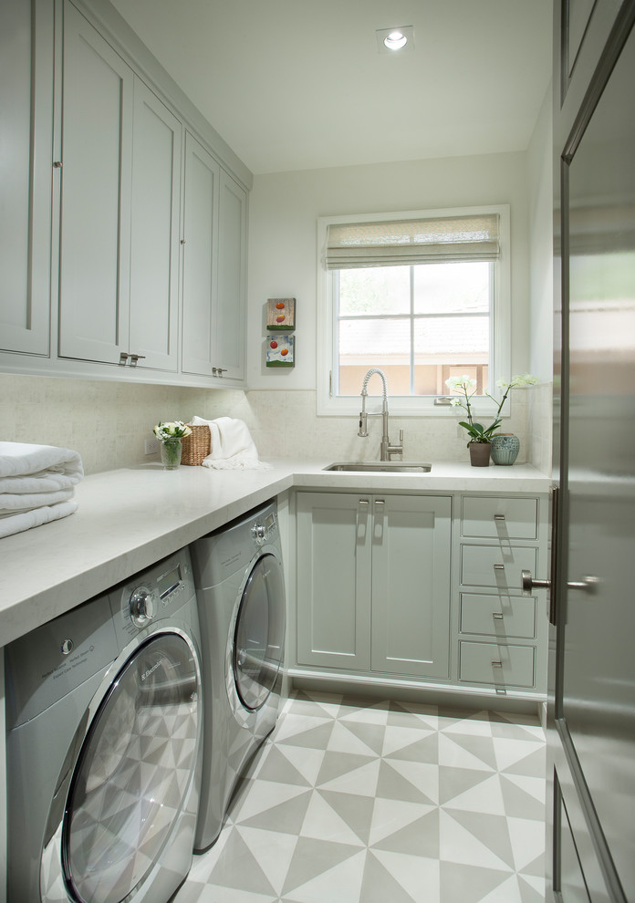 Inspiration för klassiska l-formade vitt tvättstugor enbart för tvätt, med en enkel diskho, skåp i shakerstil, grå skåp, vita väggar, en tvättmaskin och torktumlare bredvid varandra och flerfärgat golv