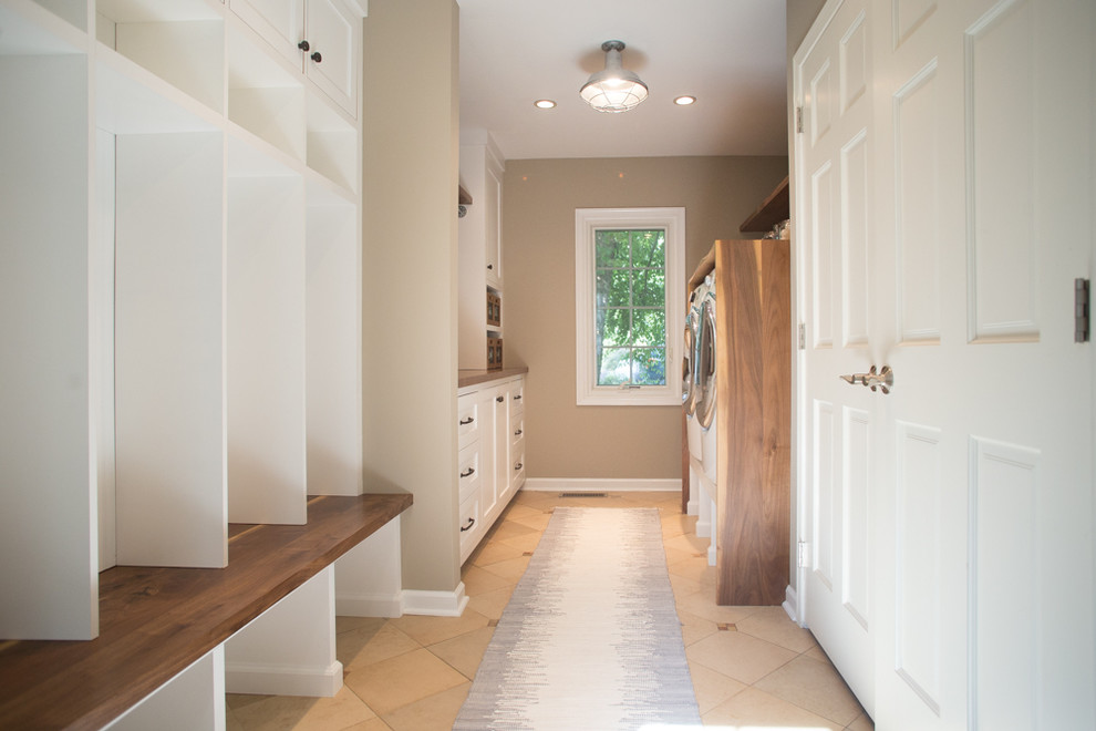 Example of a large transitional galley ceramic tile utility room design in Philadelphia with shaker cabinets, white cabinets, wood countertops, beige walls, a side-by-side washer/dryer and brown countertops