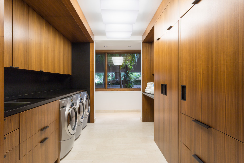 Photo of a large modern galley utility room in New York with a double-bowl sink, flat-panel cabinets, medium wood cabinets, granite worktops and a side by side washer and dryer.