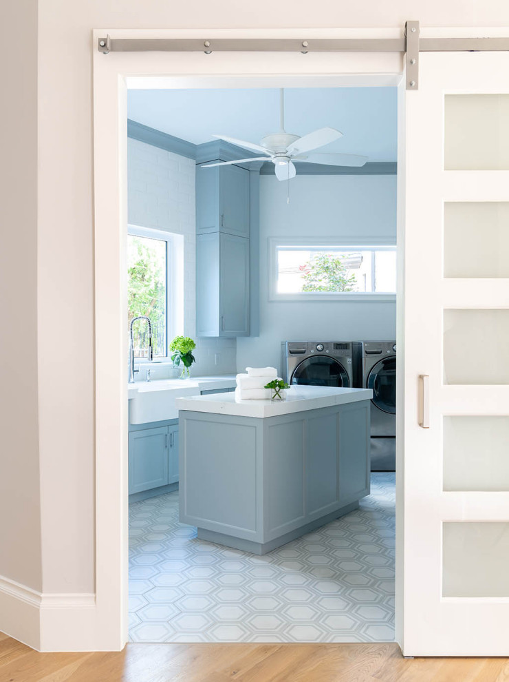 Esempio di una sala lavanderia classica con lavello stile country, ante blu, lavatrice e asciugatrice affiancate, pavimento multicolore e top bianco