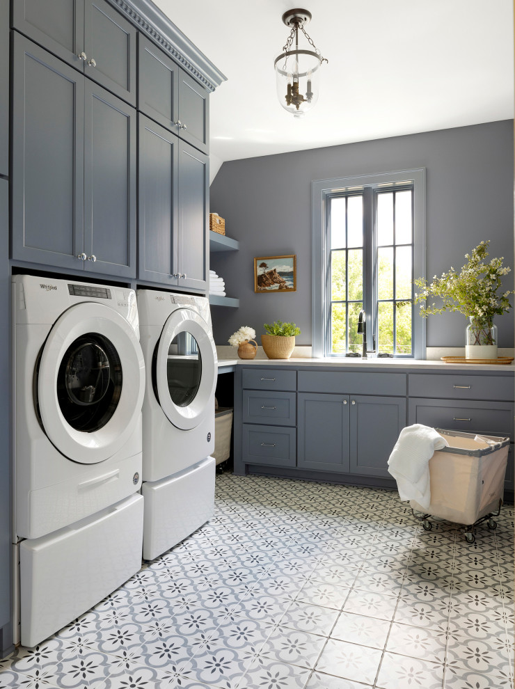 Idéer för att renovera en vintage vita l-formad vitt tvättstuga enbart för tvätt, med luckor med infälld panel, grå skåp, grå väggar, en tvättmaskin och torktumlare bredvid varandra och flerfärgat golv