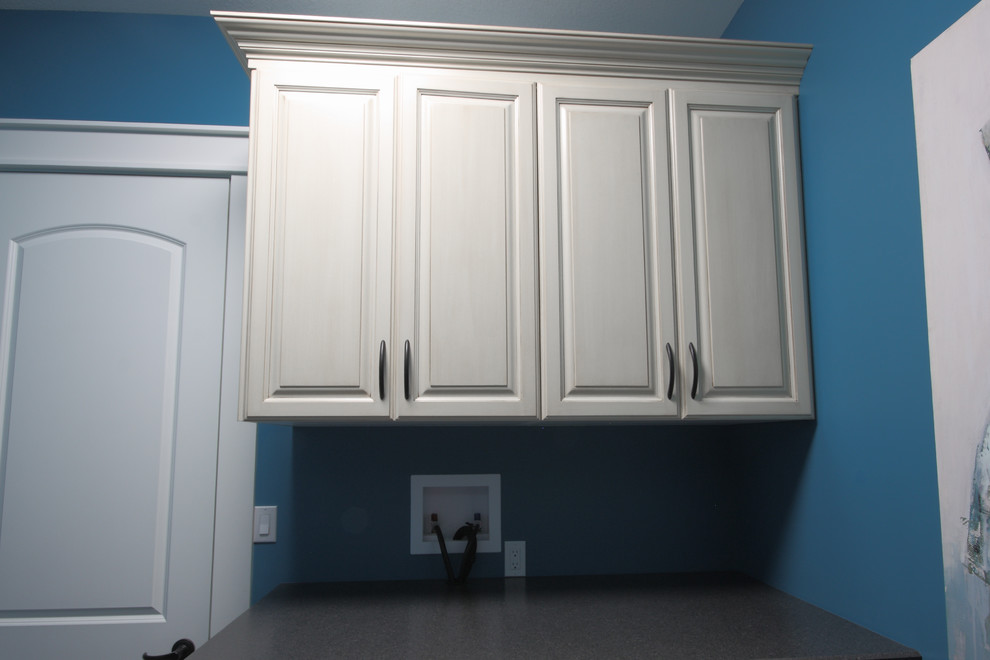 Example of a small trendy galley terra-cotta tile and gray floor dedicated laundry room design in Other with a drop-in sink, raised-panel cabinets, white cabinets, laminate countertops, blue walls and a side-by-side washer/dryer