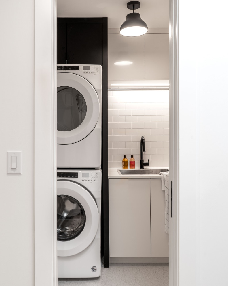 Design ideas for a contemporary separated utility room in Toronto with a built-in sink, flat-panel cabinets, white cabinets, a stacked washer and dryer, grey floors and white worktops.