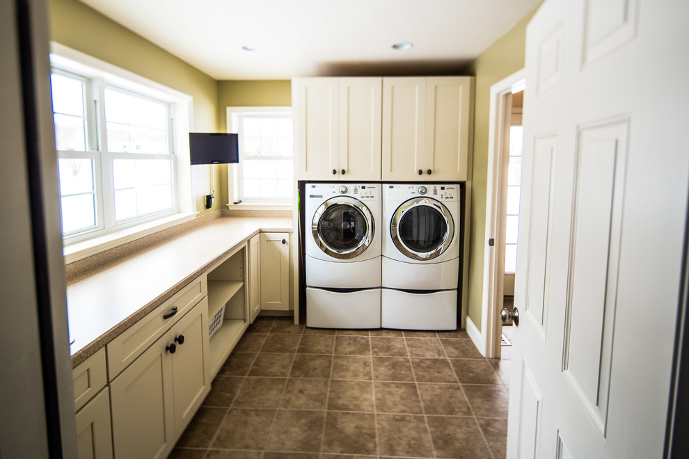 Dedicated laundry room - traditional l-shaped ceramic tile dedicated laundry room idea in Philadelphia with shaker cabinets, white cabinets, laminate countertops and a stacked washer/dryer