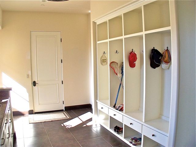 Photo of a mediterranean l-shaped utility room in San Luis Obispo with flat-panel cabinets, white cabinets, beige walls and porcelain flooring.