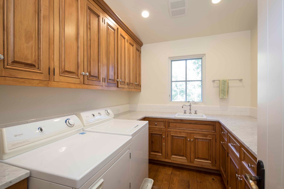 Inspiration for a large mediterranean u-shaped separated utility room in Santa Barbara with a built-in sink, beaded cabinets, medium wood cabinets, marble worktops, white walls, medium hardwood flooring and a side by side washer and dryer.