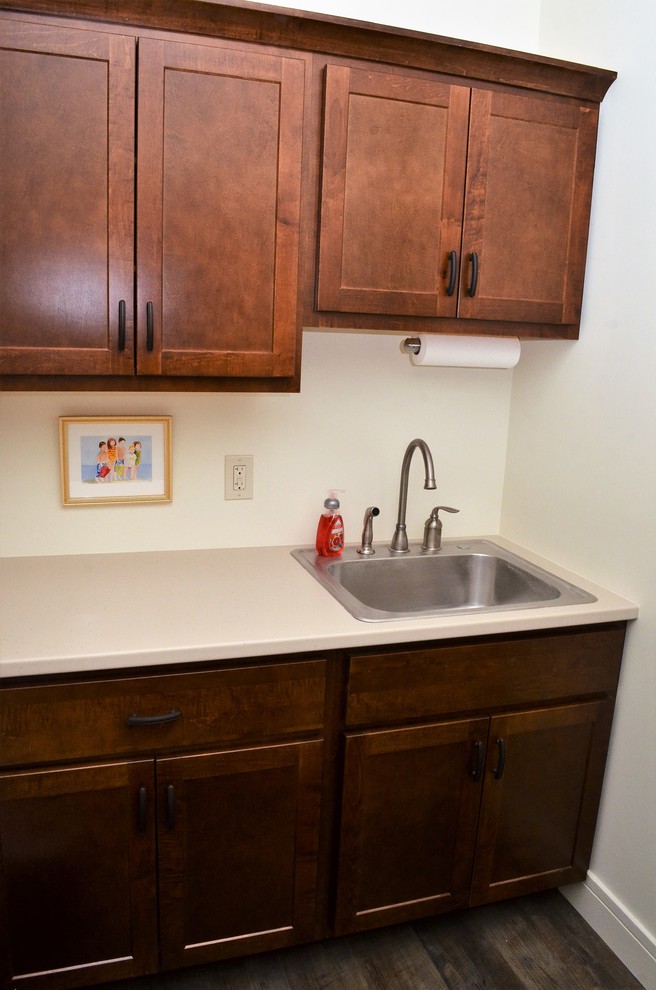 Foto di una piccola sala lavanderia chic con ante in stile shaker, ante in legno bruno, pareti bianche, parquet scuro, lavatrice e asciugatrice affiancate e pavimento marrone