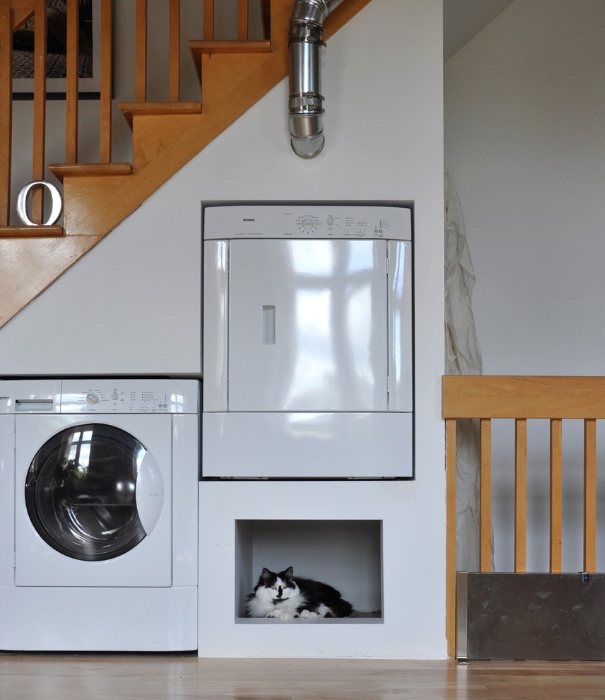 Stilmix Hauswirtschaftsraum mit weißer Wandfarbe und Waschmaschine und Trockner nebeneinander in Montreal