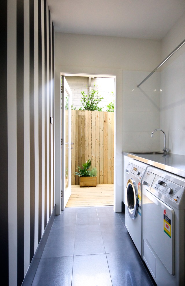 Small contemporary single-wall separated utility room in Sydney with flat-panel cabinets, white cabinets, stainless steel worktops, white walls, ceramic flooring and a side by side washer and dryer.