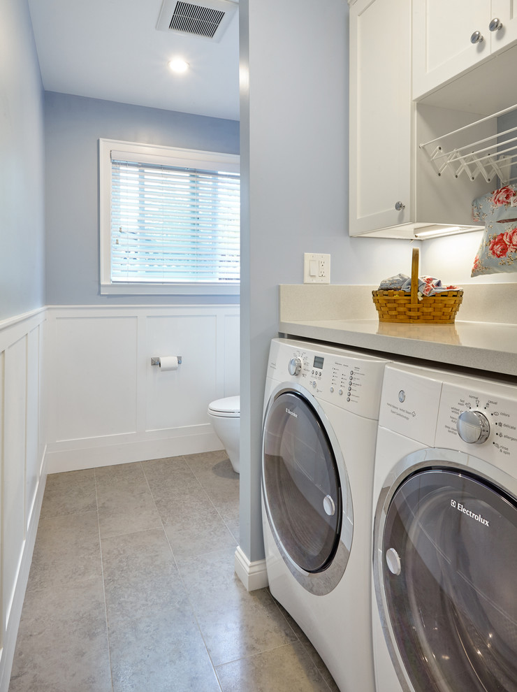 Immagine di una piccola lavanderia multiuso classica con ante in stile shaker, ante bianche, top in quarzo composito, pareti blu, pavimento in gres porcellanato e lavatrice e asciugatrice affiancate
