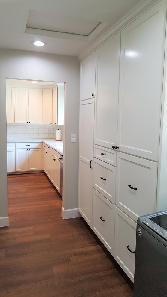 Foto di una lavanderia multiuso minimal con ante in stile shaker, ante bianche, pavimento in legno massello medio e pavimento marrone