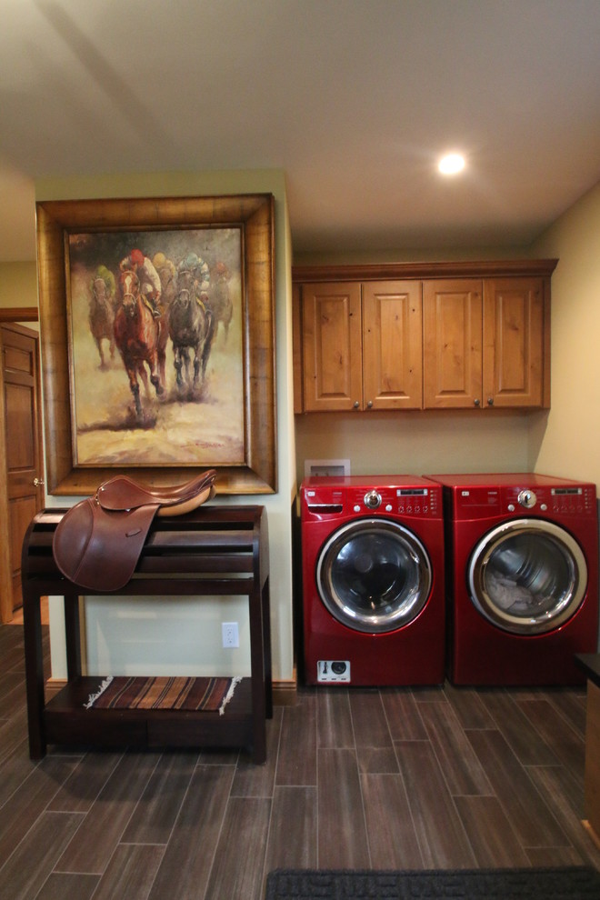 Exempel på ett mellanstort klassiskt l-format grovkök, med en nedsänkt diskho, luckor med upphöjd panel, skåp i mellenmörkt trä, granitbänkskiva, gula väggar, klinkergolv i porslin, en tvättmaskin och torktumlare bredvid varandra och brunt golv