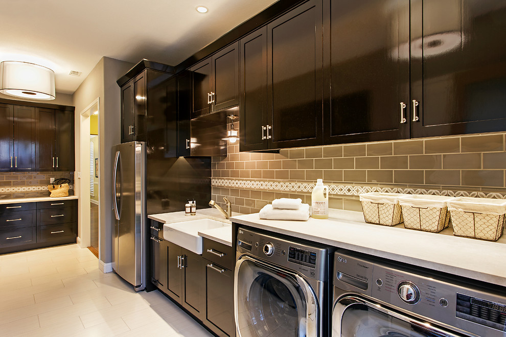 This is an example of a traditional utility room in Austin with a belfast sink, black cabinets, marble worktops, beige walls, porcelain flooring and a side by side washer and dryer.