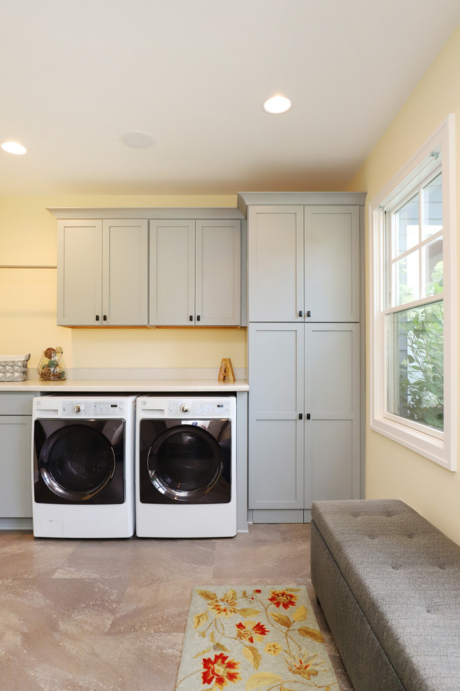 Immagine di una lavanderia multiuso chic di medie dimensioni con ante in stile shaker, ante bianche, top in laminato, pareti gialle, pavimento in laminato, lavatrice e asciugatrice affiancate e pavimento beige